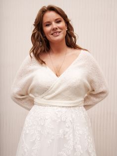 a woman in a white dress posing for the camera with her hands on her hips