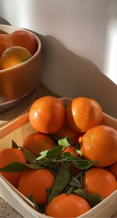 there are many oranges in the box on the counter top next to each other