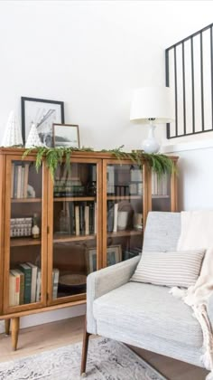 a living room with a chair, bookcase and rug in front of the fireplace