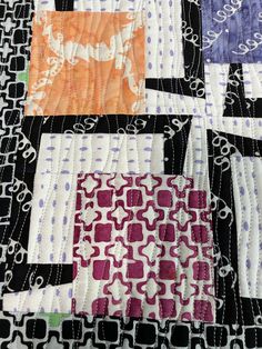 a close up of a quilt with different colored squares and designs on the fabric,