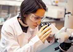 a female scientist looking through a microscope