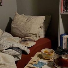 a red couch sitting next to a bookshelf filled with books and other items