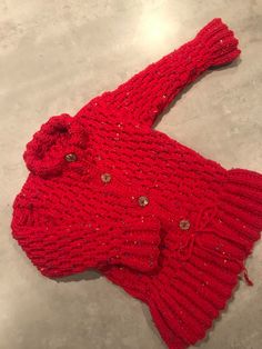 a red knitted sweater laying on top of a table