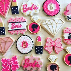 decorated cookies are arranged on a table with pink and black accents, such as bows, diamonds, lipstick, hair clips, and more