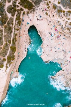 an aerial view of people swimming in the water near a sandy beach with blue waters