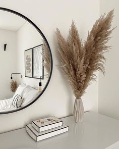 there is a mirror on the wall above a bed and a vase with dry grass in it