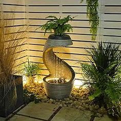 an outdoor fountain surrounded by plants and rocks