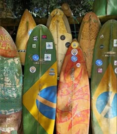 several surfboards are lined up in a row on the wall, with stickers attached to them