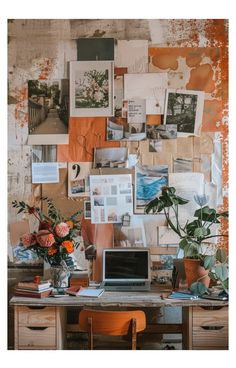 a desk with a laptop computer on top of it next to a wall covered in pictures