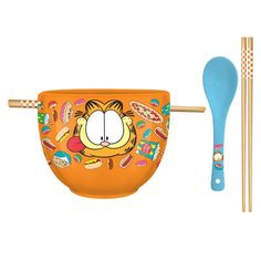 an orange bowl with chopsticks next to it and a blue spoon on the side