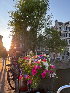 a bicycle parked on the side of a street next to flowers and buildings with people walking by