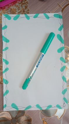 a green pen sitting on top of a piece of paper next to some ribbons and bows