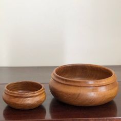 two wooden bowls sitting on top of a table