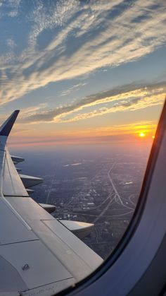 an airplane wing with the sun setting in the background