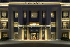 the marco polo hotel is lit up at night with lights on it's front entrance