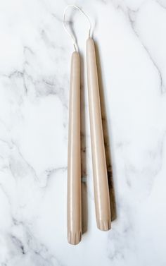 two candles sitting on top of a white marble counter next to each other, one with a single candle sticking out of it