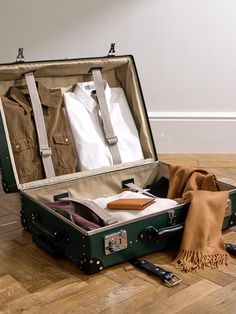 an open suit case on the floor with clothes in it