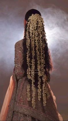 the back of a woman's head with long, curly hair and flowers on it