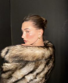 a woman wearing a fur coat and earrings