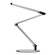 a desk lamp that is on top of a white surface and has a black base