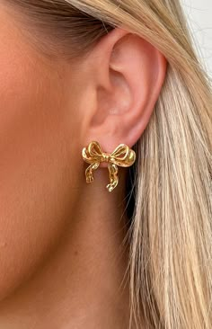 Calista Gold Bow EarringsHow to Style:2024 is really our croquette era! Elevate any with these gold bow earrings. Enhance your look further with more gold Features: 18K Gold Plated 1 x gold bow earrings set Stud earrings Jewellery Moodboard, Classy Gold Earrings, Earrings 2024, Earrings Trend 2024, Chic Gold Earrings With Bow, Gold Earrings Aesthetic, Gold Dainty Earrings With Bow, Bow Earrings Gold, Gold Bow Earrings