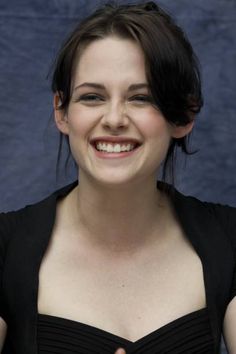 a woman smiling and wearing a black dress