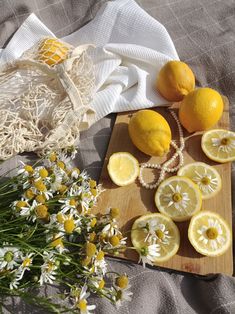 lemons and daisies are on a cutting board next to a drawstring bag