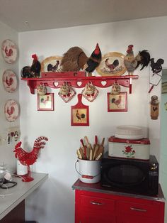 a kitchen with red cabinets and rooster decorations on the wall