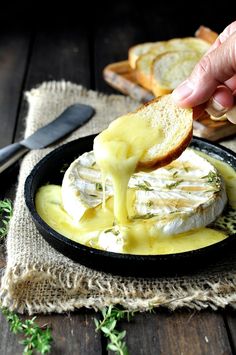 a person dipping cheese onto bread in a skillet