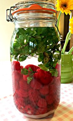 a mason jar filled with strawberries and green leaves