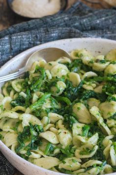 a white bowl filled with pasta and spinach