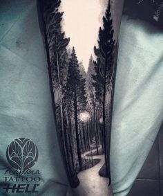 a man's arm with a black and white forest scene on the left forearm