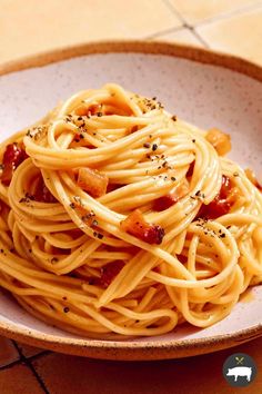 a white bowl filled with spaghetti and bacon