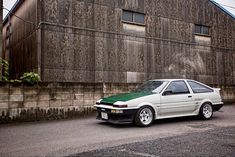 a white car parked in front of a wooden building with graffiti on it's side