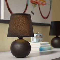 a lamp sitting on top of a white table next to a book and some books