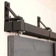 a black shelf with two metal brackets on it's sides and one is attached to the wall