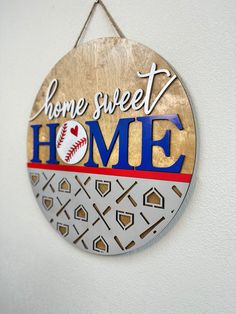 a sign that says home sweet home hanging from a wall with baseballs on it