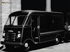 black and white photograph of an old delivery truck parked in front of a brick building