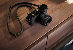 a camera sitting on top of a wooden table next to a green cord and an object