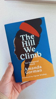 a person holding up a book with the title, the hill we climb an industrial poem