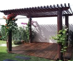 a wooden deck with potted plants on it and a pergolated area in the background