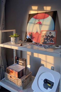 a shelf with various items on it in the corner next to a wall mounted painting