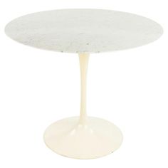 an oval marble table with a white base on a white background in the shape of a tulip