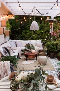 an outdoor living room with lots of plants and lights