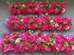 three rows of pink flowers are arranged in the shape of rectangles on a gray surface