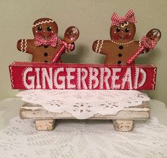 two gingerbread men are on top of a wooden sign that says gingerbread with white lace