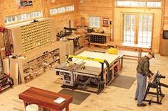 a man working in a wood shop surrounded by workbenches and tables with tools