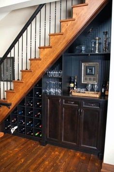 a wine rack under the stairs in a home with wooden floors and dark wood cabinets