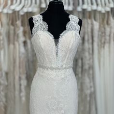 a white wedding dress is on display in front of some racks of dresses and gowns