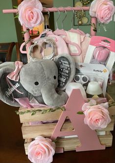 a baby girl gift basket with pink roses and an elephant stuffed animal in the middle